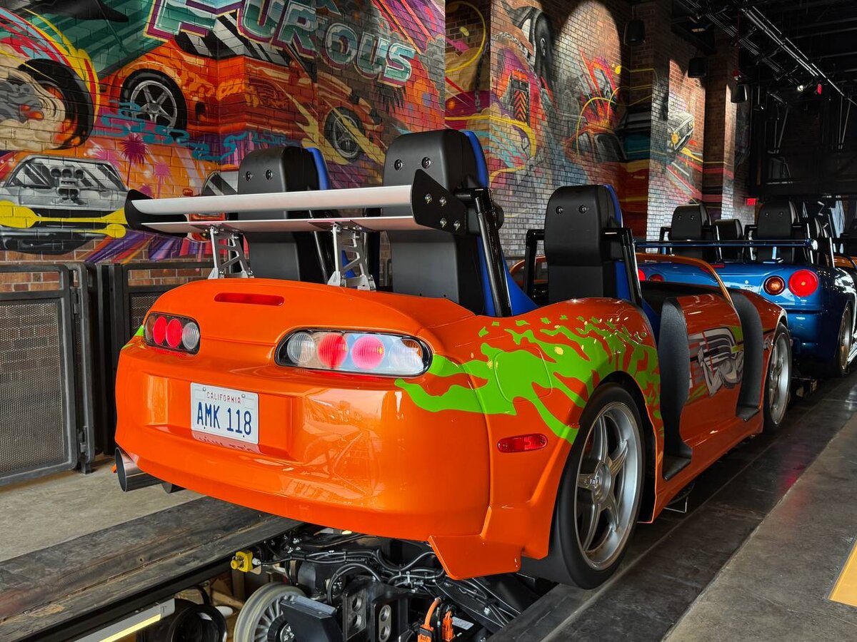 Rear view of Brian's Supra and Skyline GT-R ride vehicles with Tristan Eaton mural at Fast & Furious: Hollywood Drift