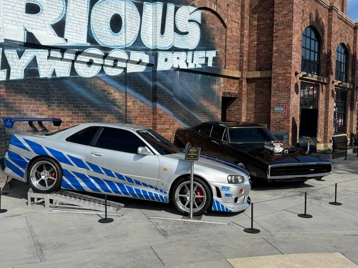 Close-up of Brian's Nissan Skyline GT-R R34 with blue flowing graphics and Dom's Dodge Charger at Universal Studios Hollywood