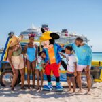 Family with Mickey Mouse on a beach with a Disney Cruise Line ship in the background, promoting Disney Cruise Line kids 50 percent off fares