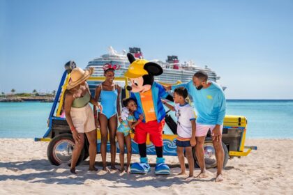 Family with Mickey Mouse on a beach with a Disney Cruise Line ship in the background, promoting Disney Cruise Line kids 50 percent off fares