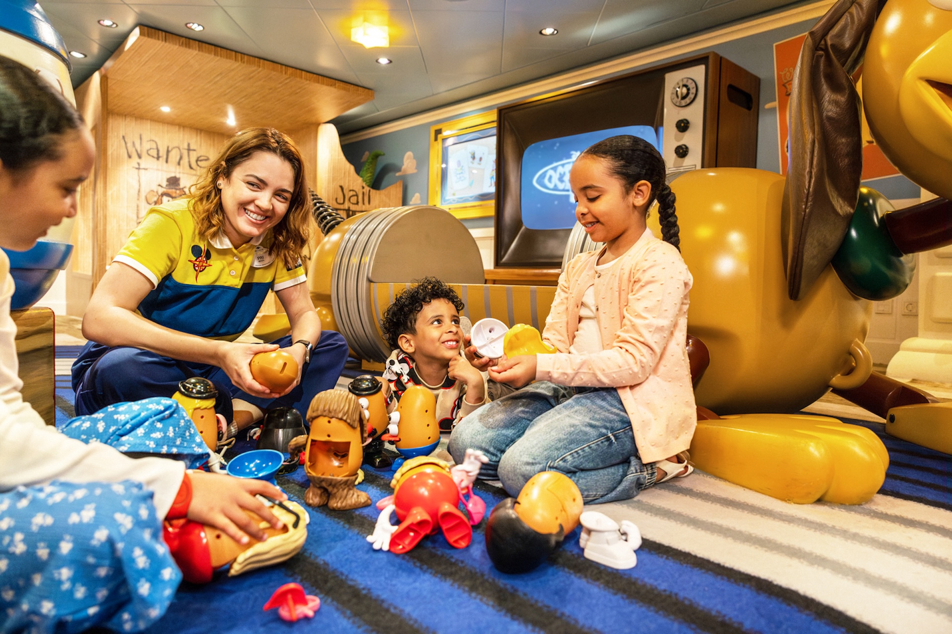 Disney Cruise Line kids club counselor plays with children using Mr. Potato Head toys in a Toy Story themed play area onboard