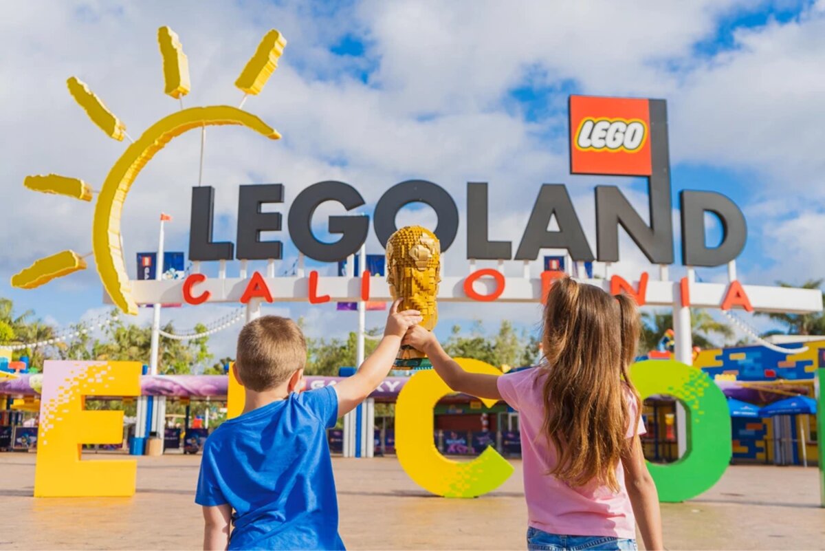 Children hold a LEGO-style trophy in front of a LEGOLAND entrance for the FIFA World Cup 2026 Experience