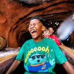 Children laugh while riding a Disneyland Resort water attraction during summer