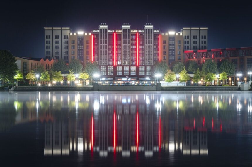 Disney Hotel New York – The Art of Marvel at Disneyland Paris lit at night, reflected in Lake Disney