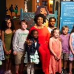 Jenifer Lewis with families inside Tiana's Joyful Celebration at The Children's Museum of Indianapolis. Photo credit: The Children's Museum of Indianapolis.