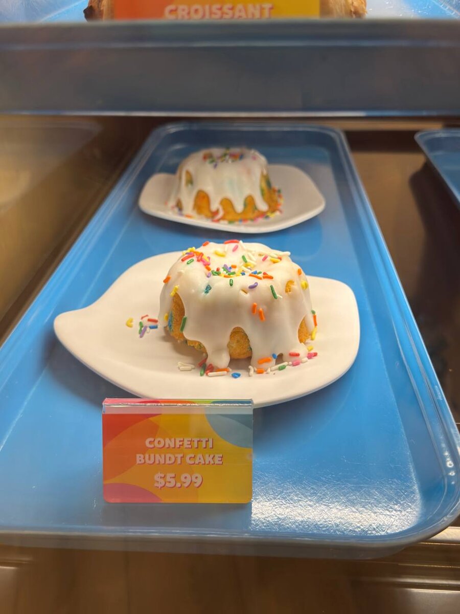 Confetti bundt cake with icing and rainbow sprinkles in the Curiosity Cafe bakery case at Universal Kids Resort