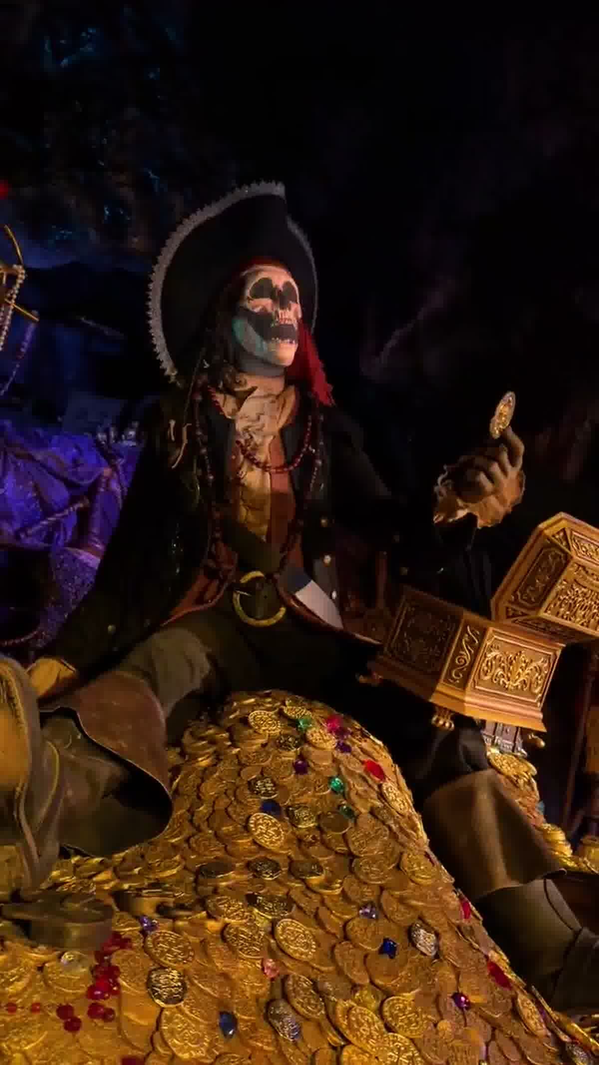 Pirate holding a coin beside treasure in Pirates of the Caribbean at Disneyland