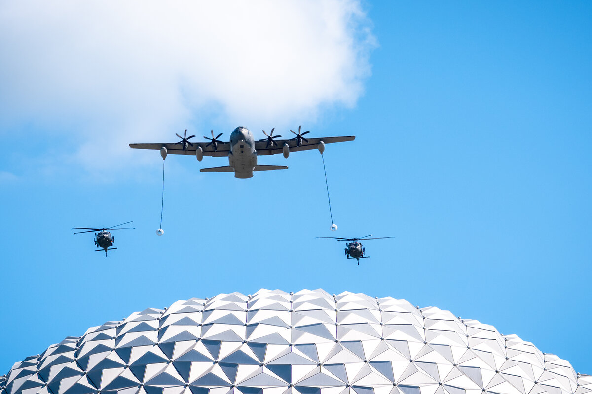 A U.S. Air Force C-130 and helicopters fly over Spaceship Earth at EPCOT during the July 4 2026 flyover