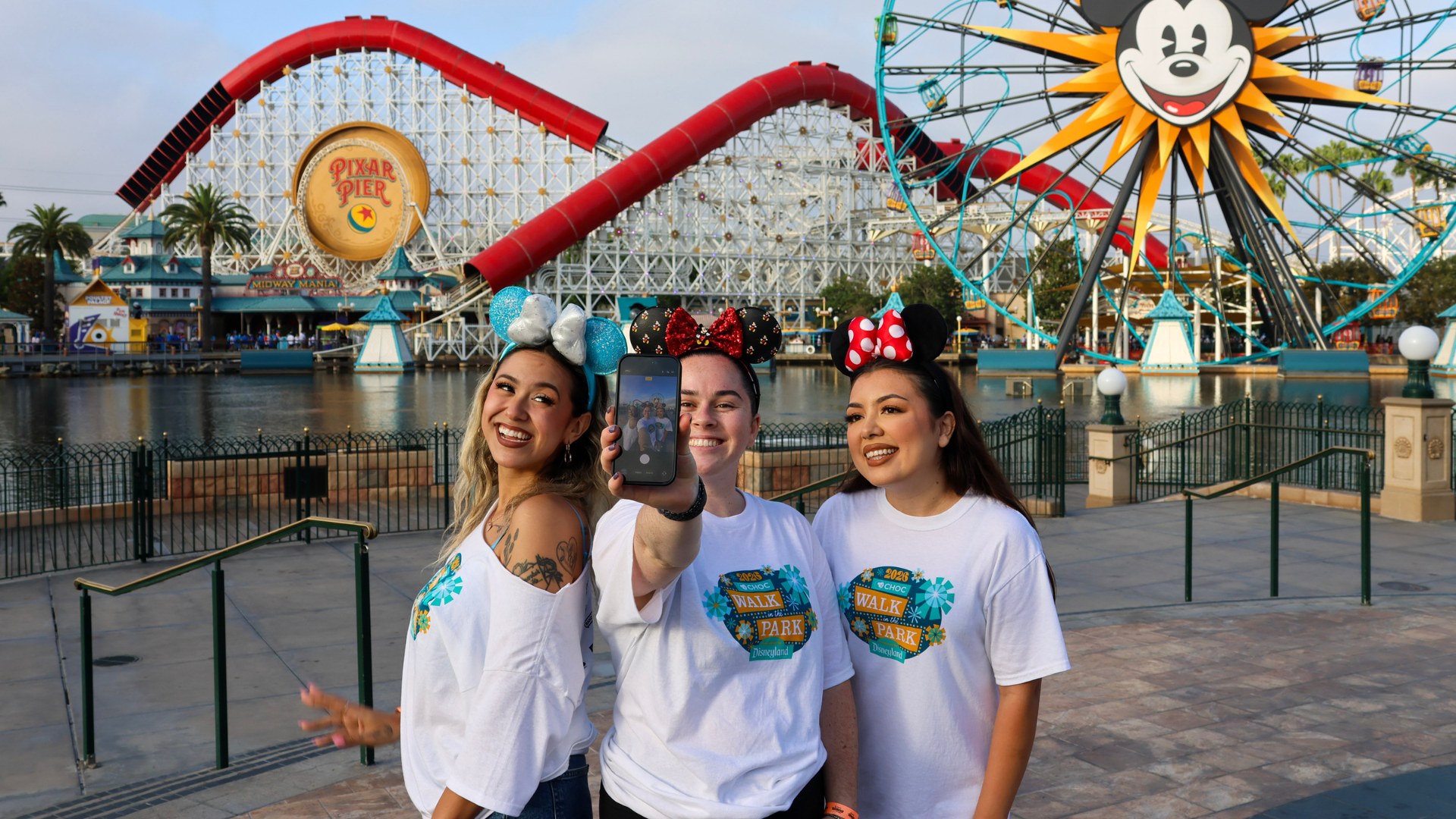 Three CHOC Walk participants taking a photo together in front of Pixar Pier