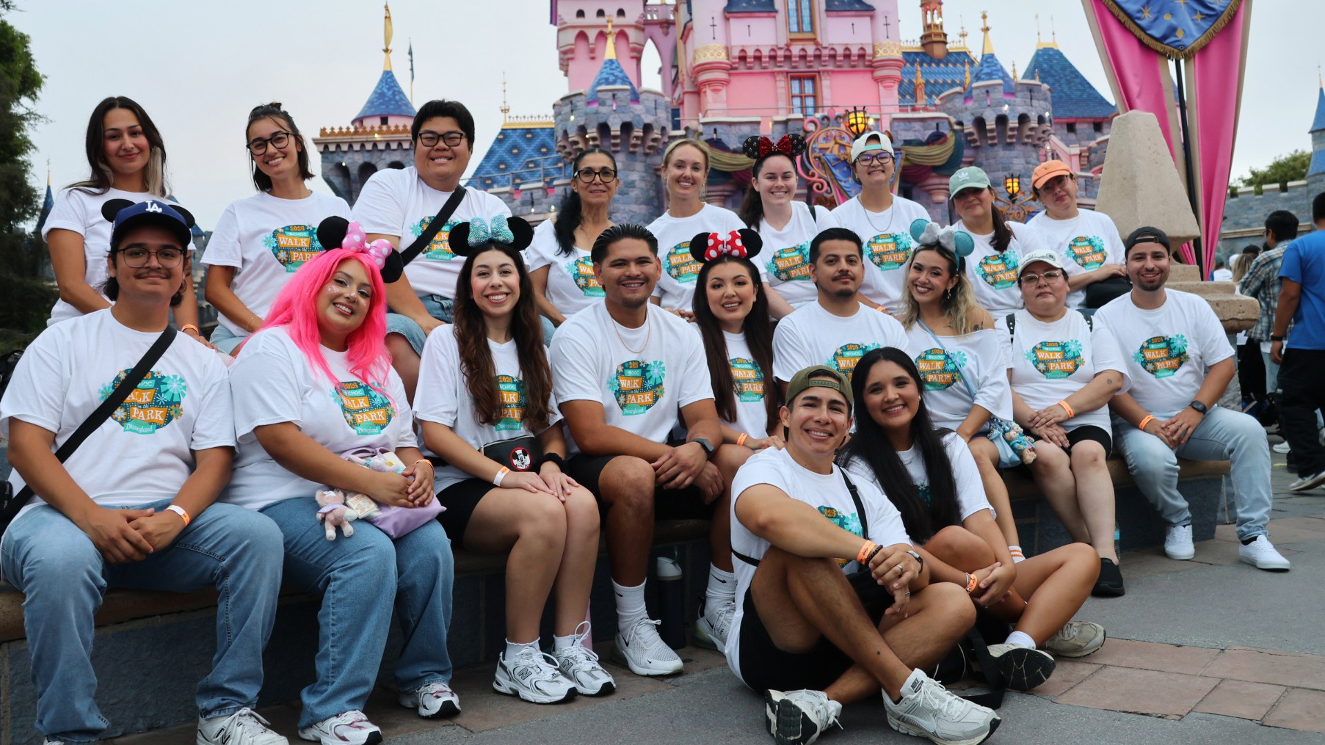 Walkers in matching CHOC Walk in the Park shirts gathered in front of Sleeping Beauty Castle at Disneyland