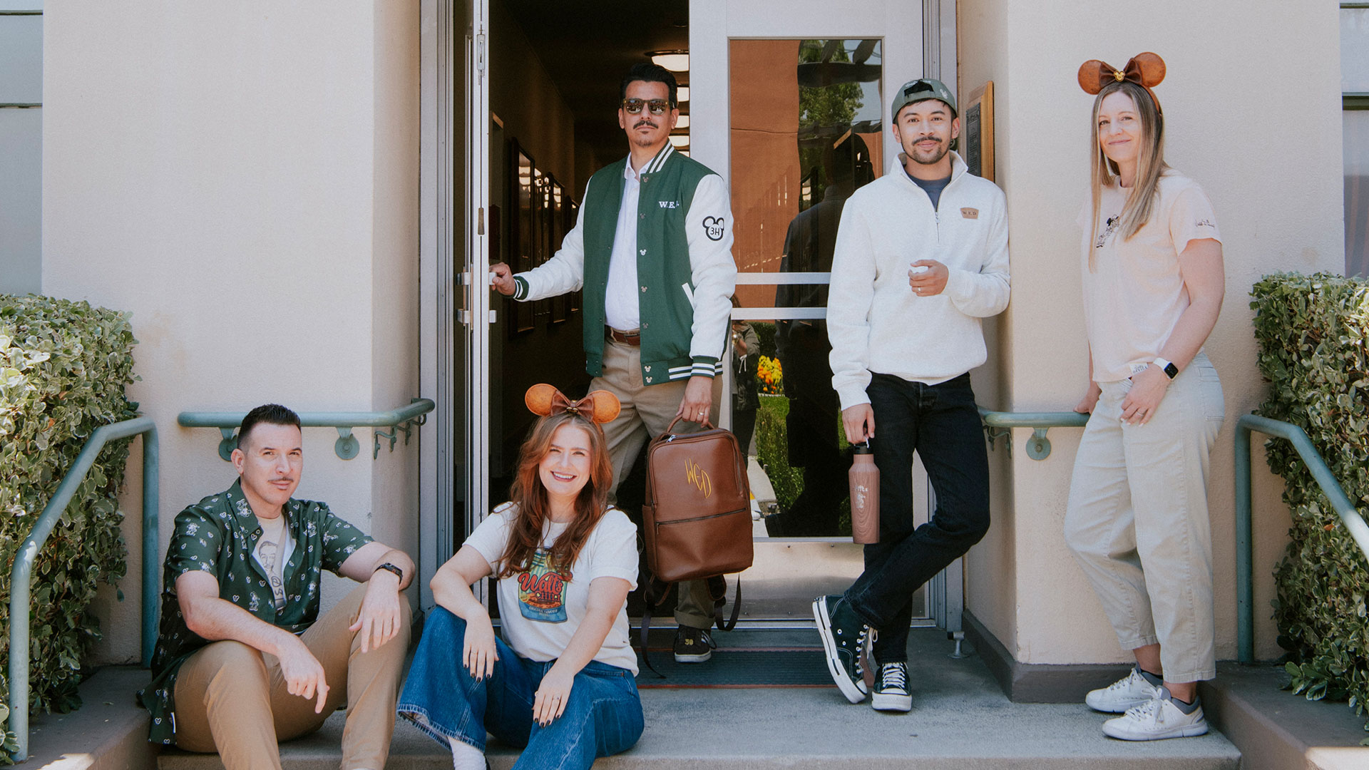 Models wearing and holding pieces from the Walt's Office merchandise collection outside the Animation Building at The Walt Disney Studios