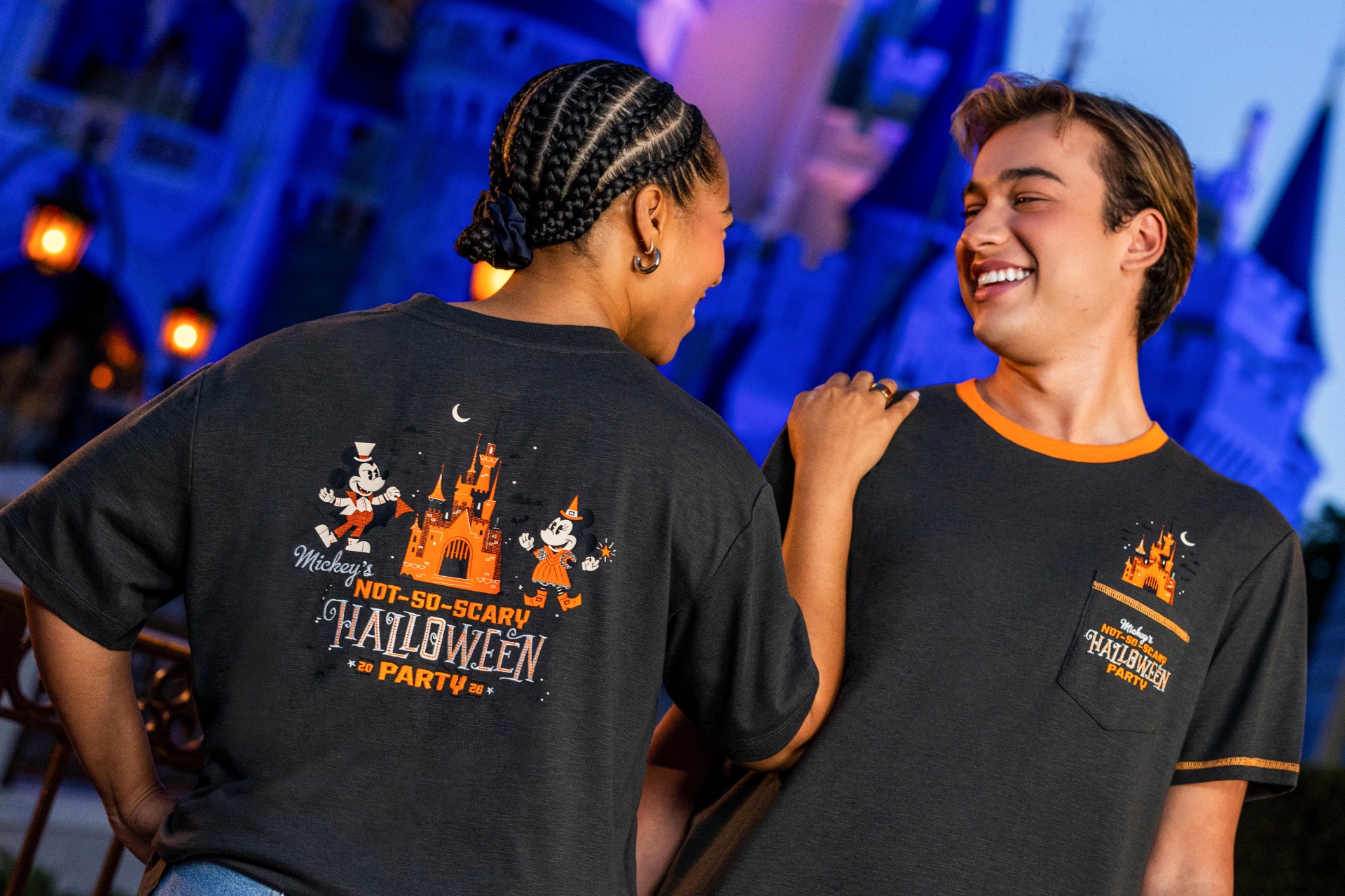 Two guests wearing gray Mickey's Not-So-Scary Halloween Party 2026 tees with orange castle artwork in front of Cinderella Castle