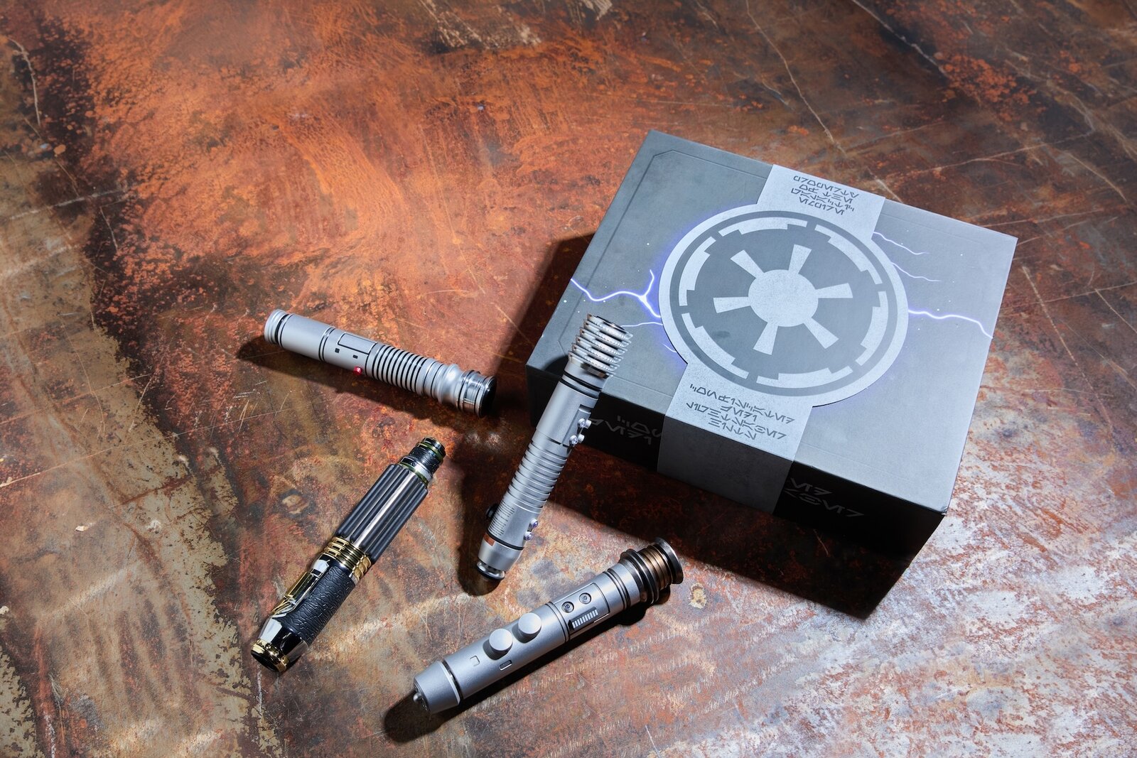 Four Legacy Lightsaber Box Set hilts beside the closed display box