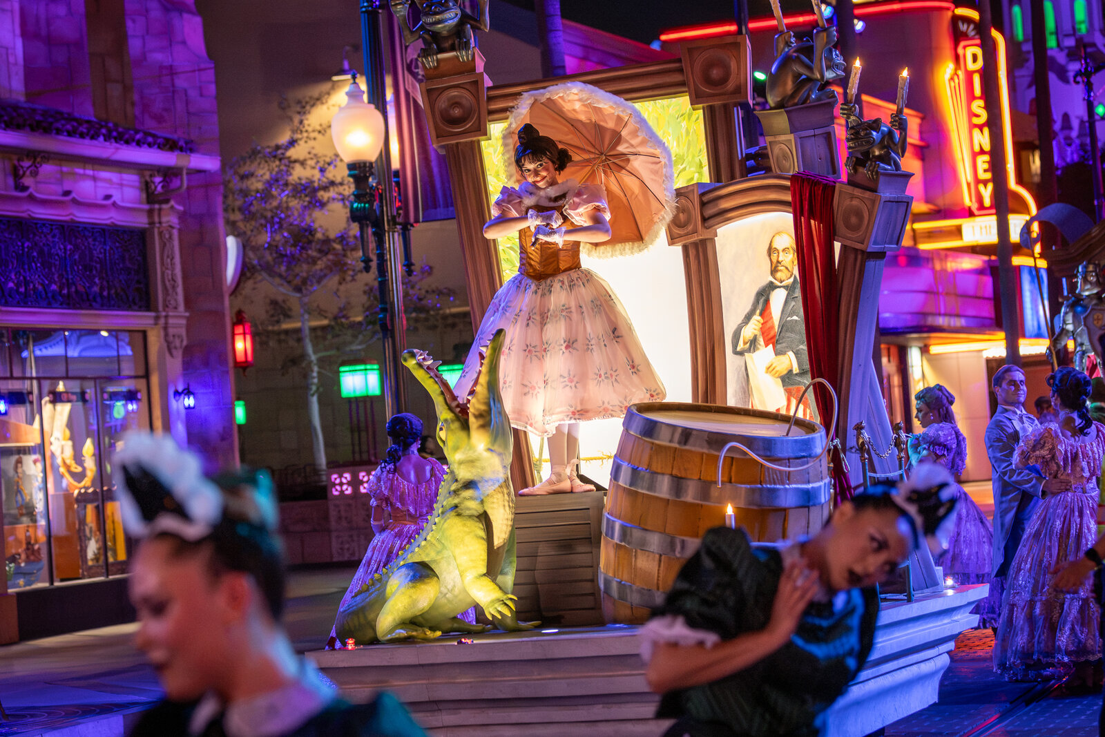 A performer with a parasol dances near a scaly creature at Madame Leota's Swinging Wake