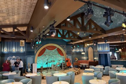 Blue lounge chairs, round tables and an arched stage inside Hurly-Burly at Disney’s BoardWalk.