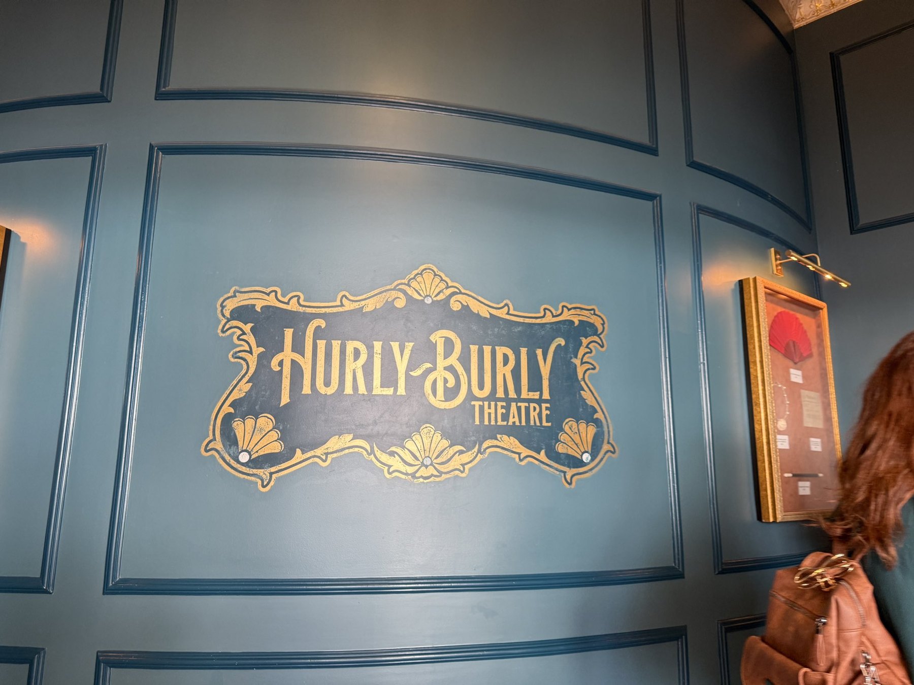 Hurly-Burly Theatre lettering and shell motifs on a blue paneled wall.
